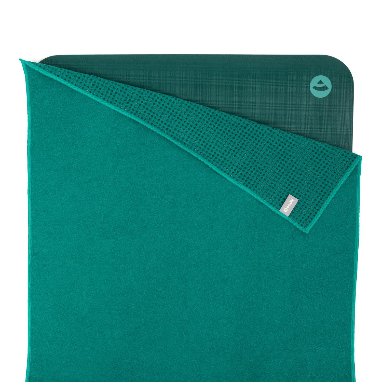 Serviette de yoga verte, pliée. Dessus lisse, dessous à picots. Logo visible.