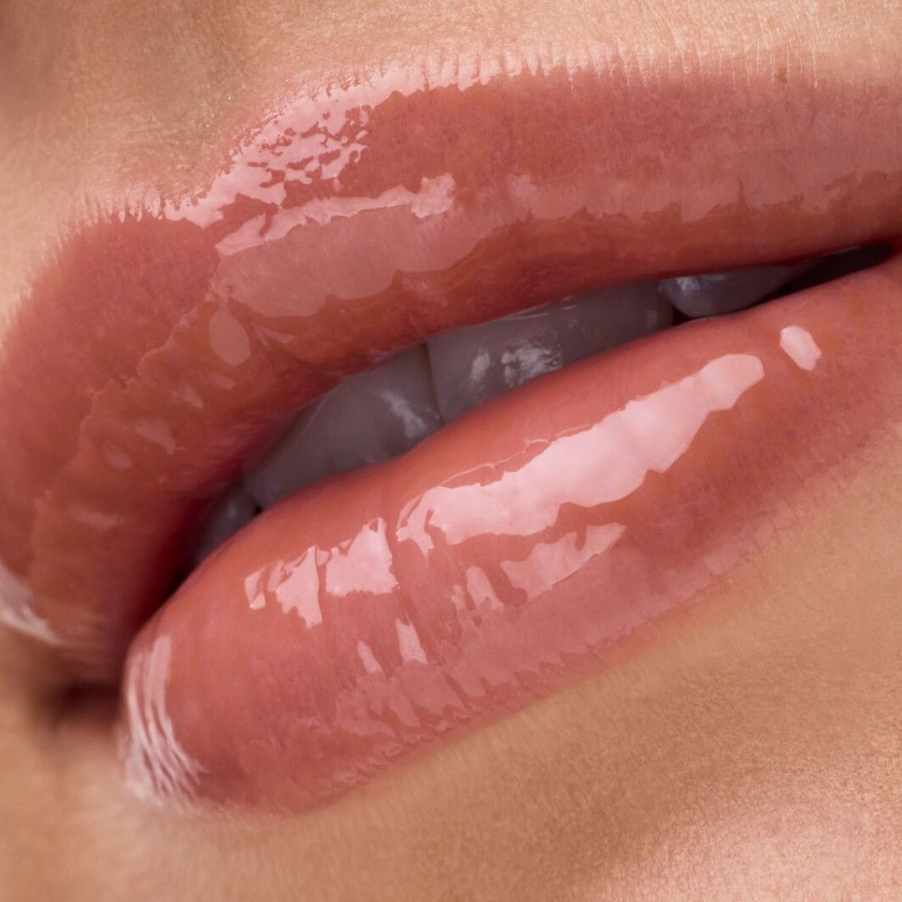 Close-up van lippen met glanzende lipgloss. De lippen zijn licht geopend, de glans is duidelijk zichtbaar.