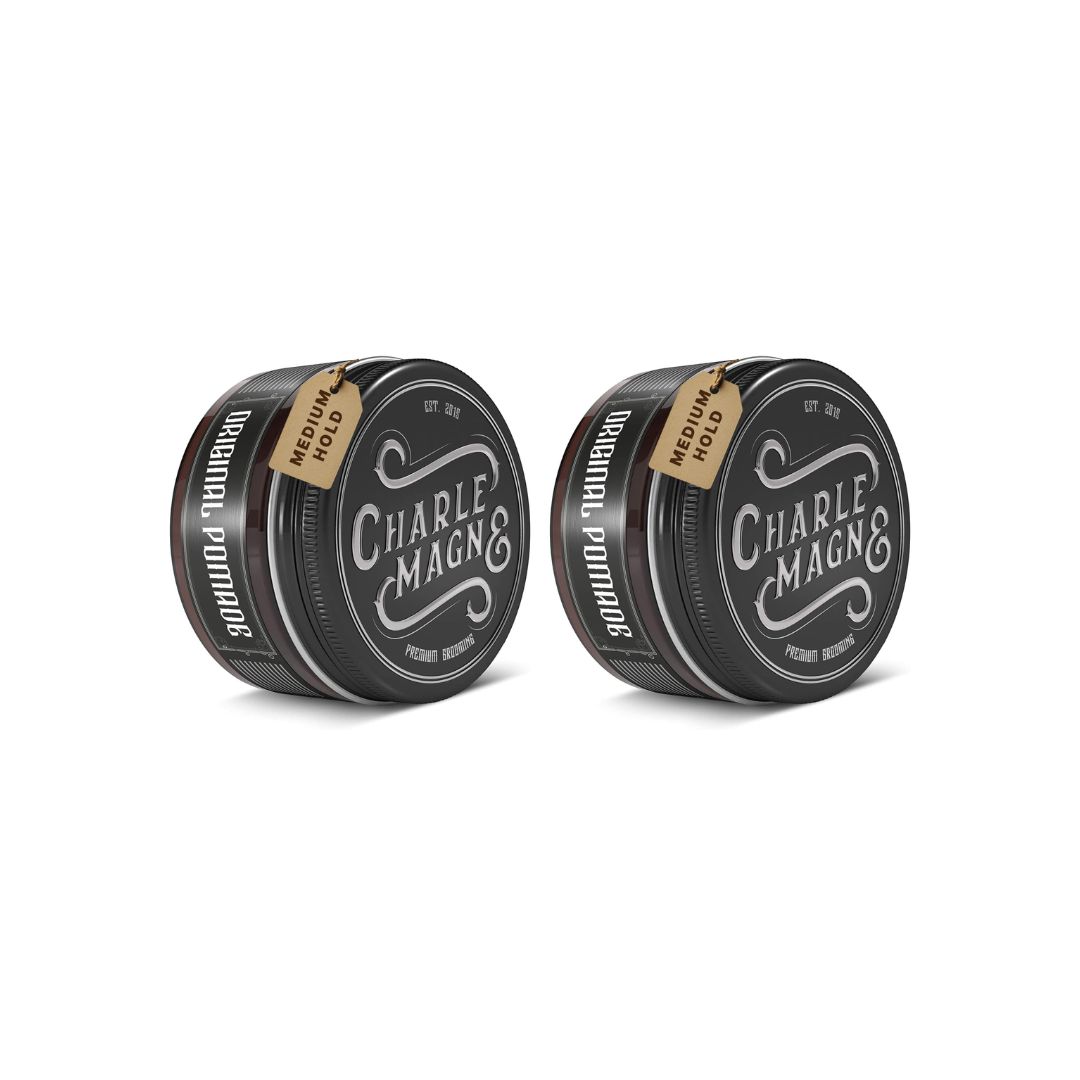 Deux boîtes rondes noires avec couvercles. Chaque boîte porte l'inscription "Charle Magne" et "Original Pomade". Chaque boîte a une étiquette "Medium Hold".