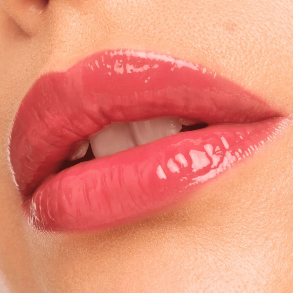 Close-up van lippen met glanzende, roze lipgloss. De lippen zijn lichtjes geopend, tanden zichtbaar.