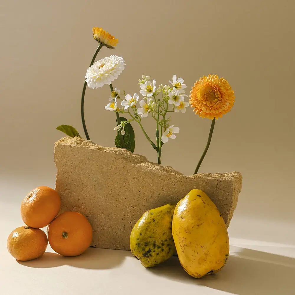 Arrangement met bloemen, mandarijnen en papaja's. Bloemen in een stenen blok.
