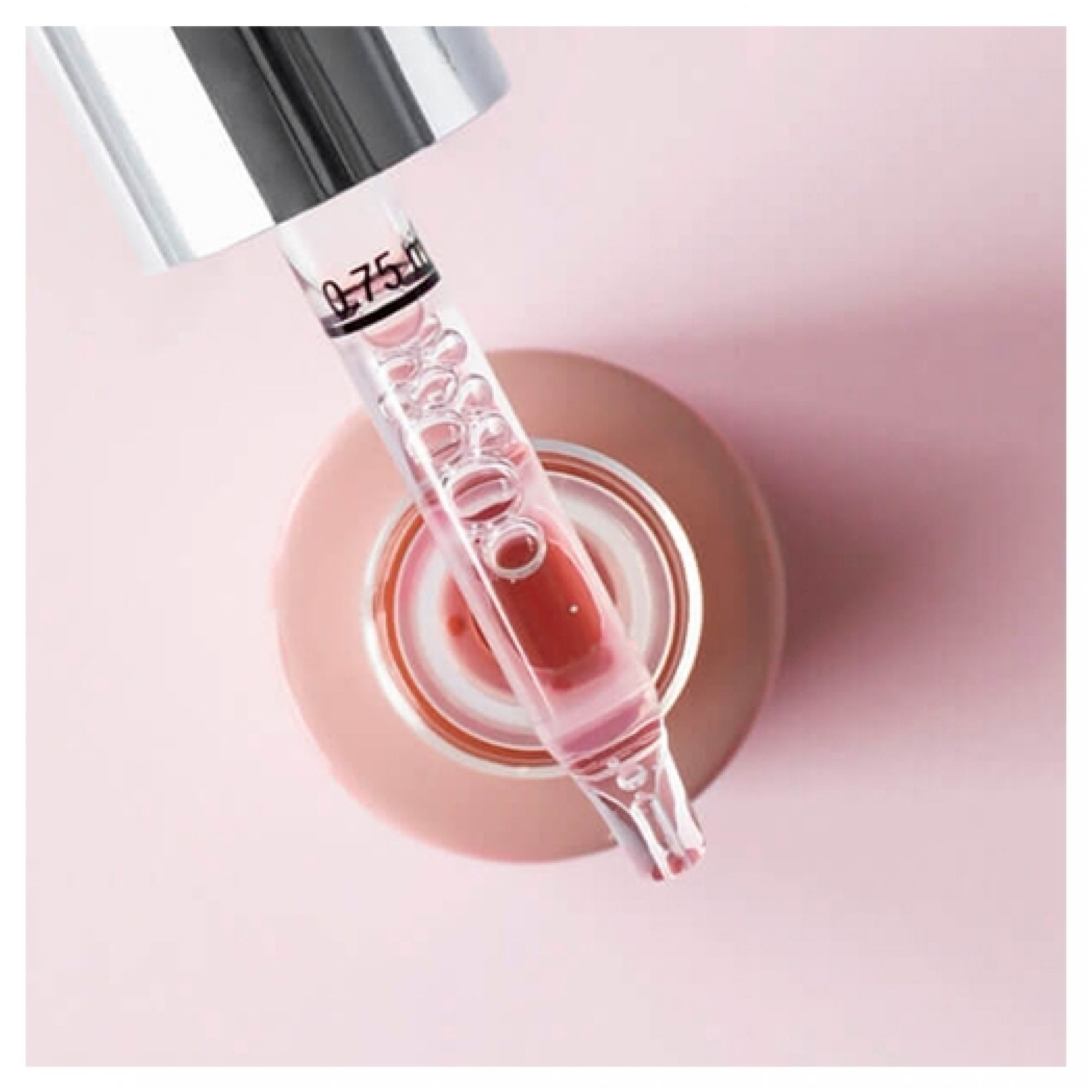 Gros plan d'une tête de pipette avec sérum rose et bulles, abaissée dans un flacon ouvert marqué 0,75 ml.