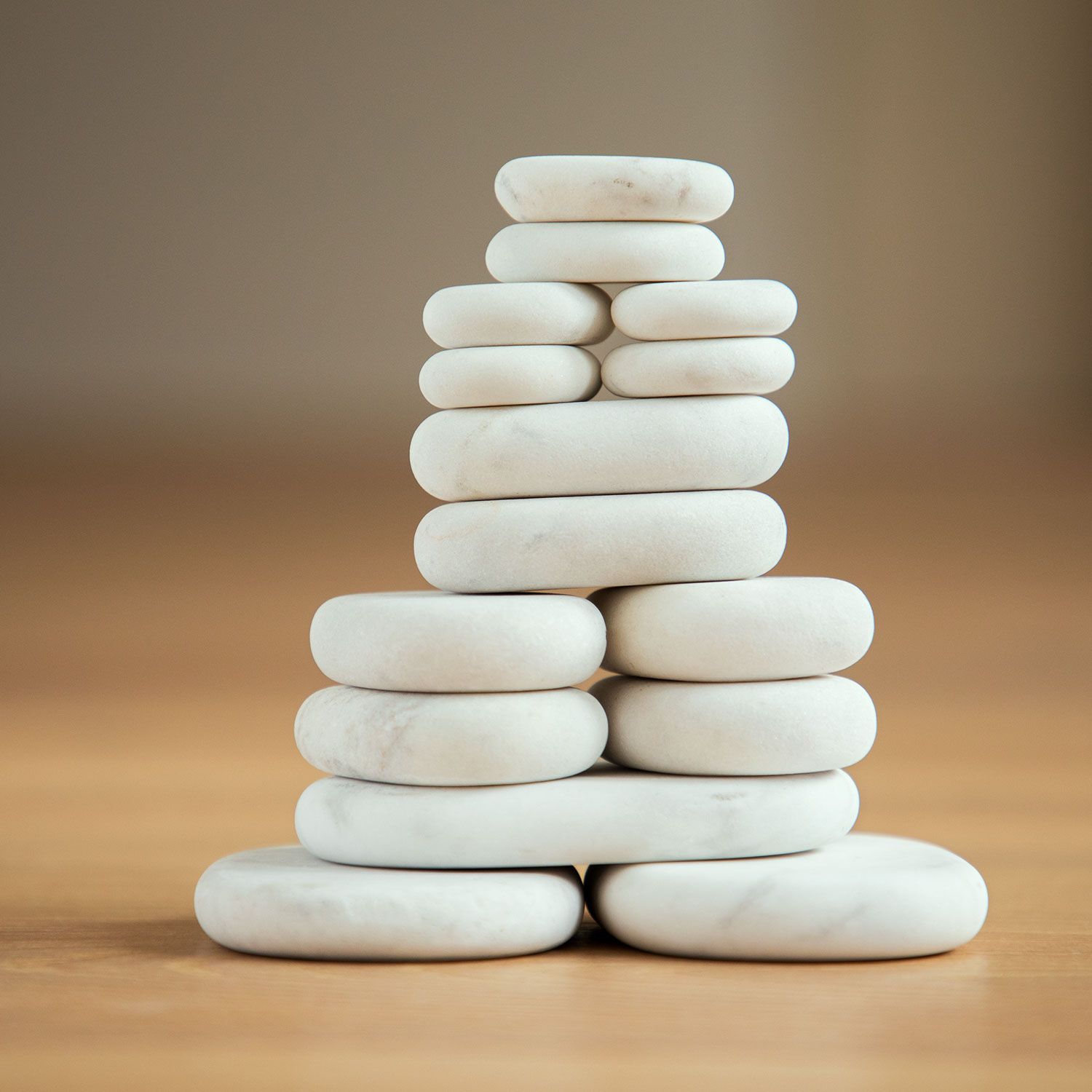 Toren van witte, ovale stenen, op houten ondergrond. Stenen van verschillende grootte gestapeld.