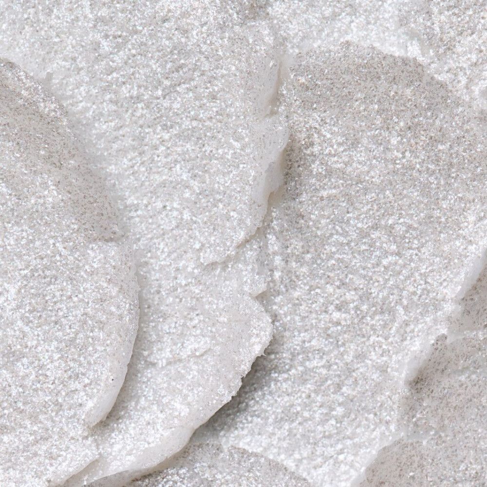 Gros plan sur un produit blanc scintillant. Forme irrégulière, peut-être du maquillage.