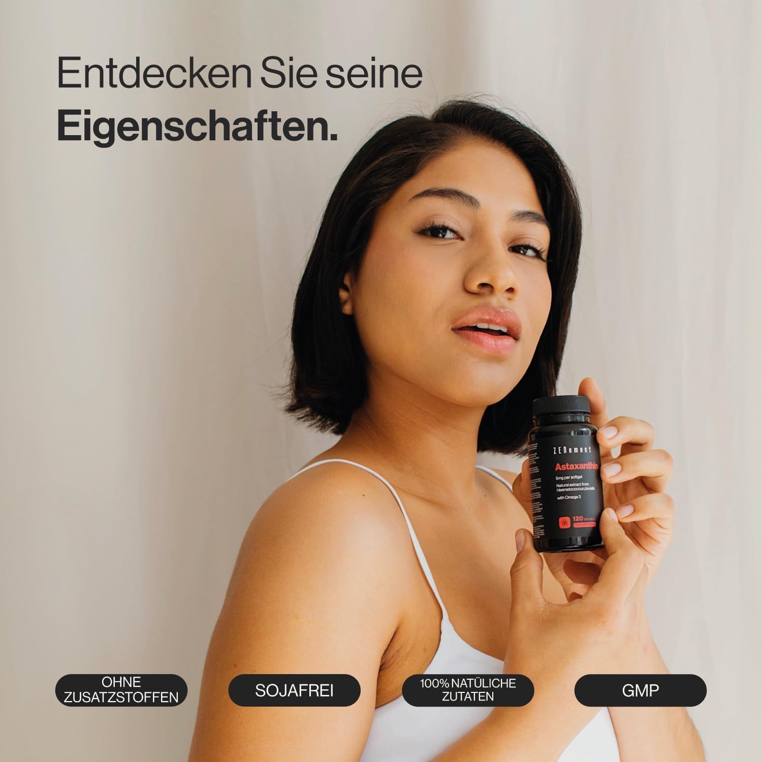 Vrouw houdt een zwarte fles met rode tekst vast. Op de fles staat Astaxanthine. Opschriften: Zonder toevoegingen, Sojavrij, 100% natuurlijke ingrediënten, GMP.
