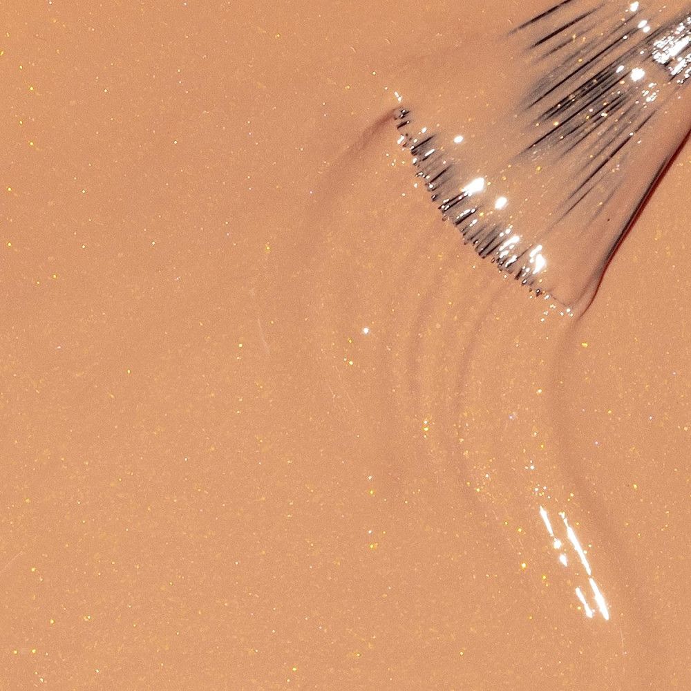 Vernis à ongles beige pailleté. Pinceau dans le vernis. Vue rapprochée.