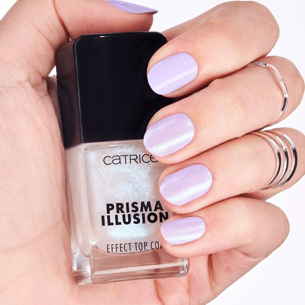 Hand met gelakte nagels en Catrice Prisma Illusion Effect Top Coat. Nagels lichtlila gelakt. Flesje met zwarte dop.