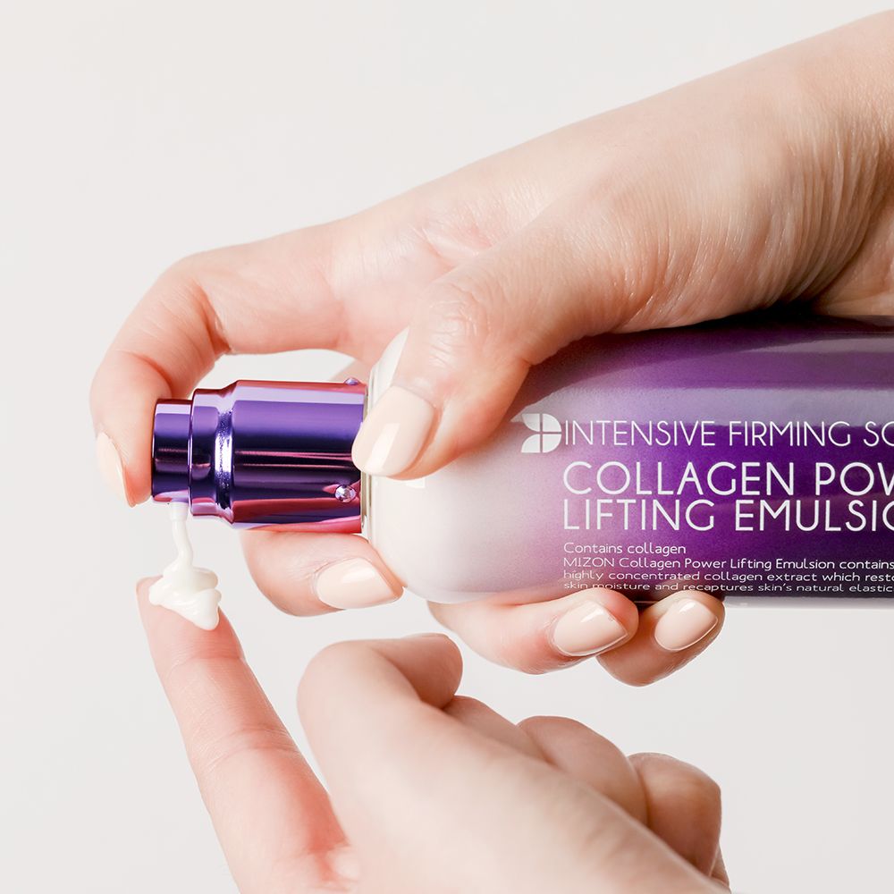 Main appuyant sur la tête de pompe du flacon MIZON Collagen Power Lifting Emulsion. Crème distribuée.