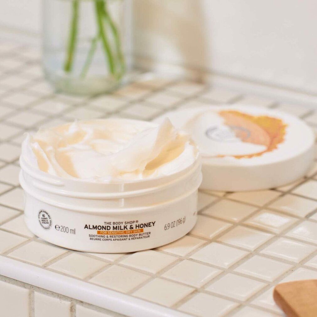 Pot de beurre corporel ouvert, avec le couvercle à côté. Inscription : Almond Milk & Honey. 200 ml.