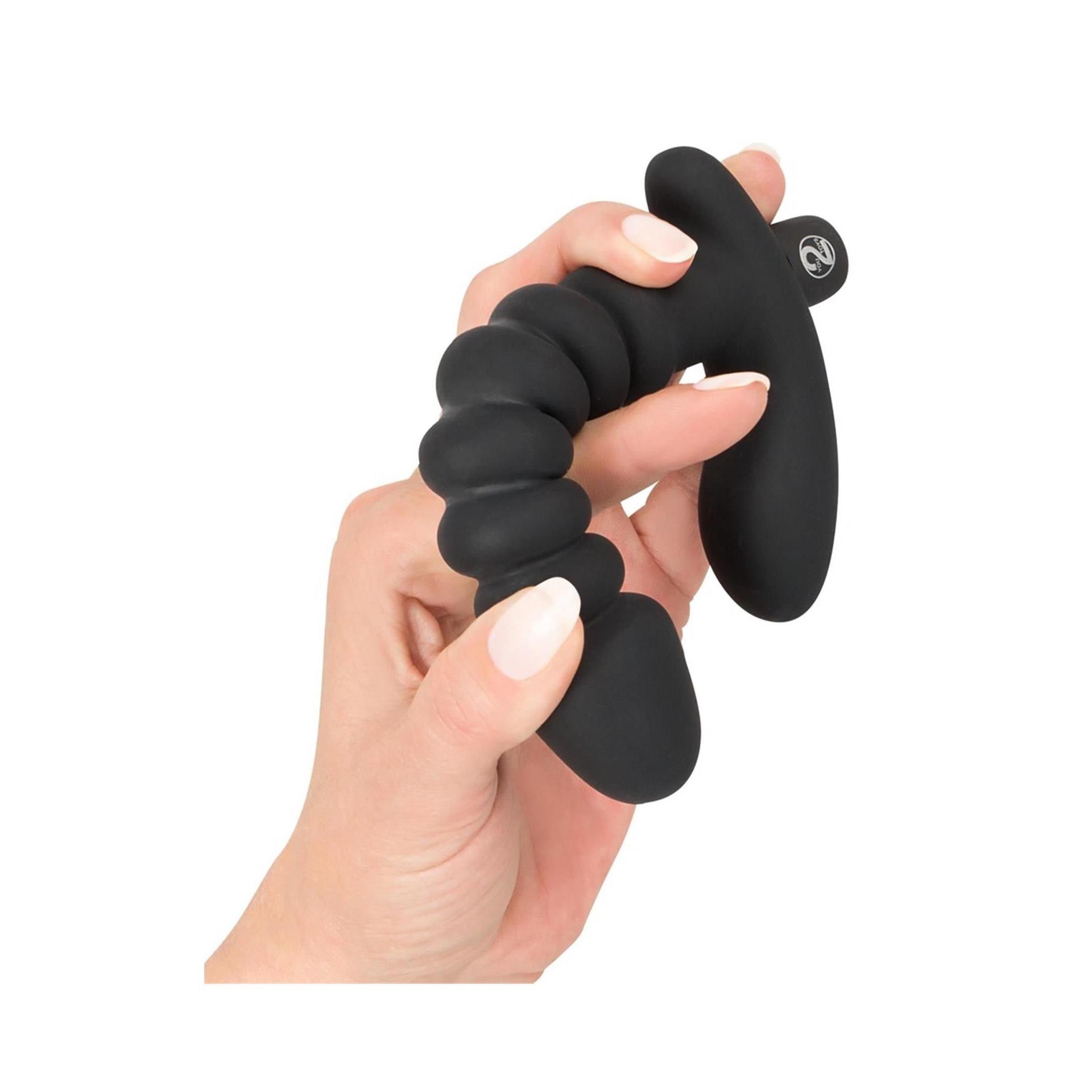 Hand die een zwarte vibrator vasthoudt, geribbelde schacht en gebogen handvat.