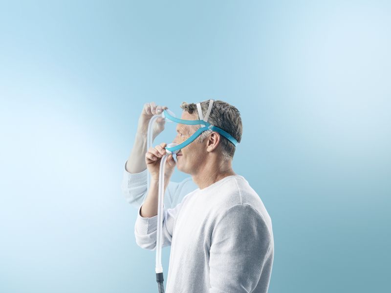 Un homme met un masque nasal avec raccord de tube.