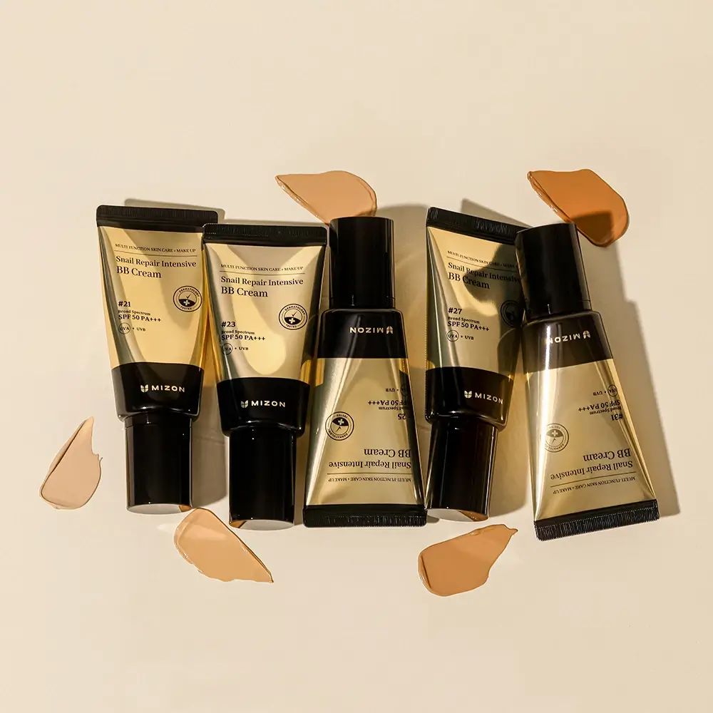 Vijf tubes BB Cream, merk MIZON, met kleurstalen. Gouden tubes met zwarte dop. Op lichte achtergrond.