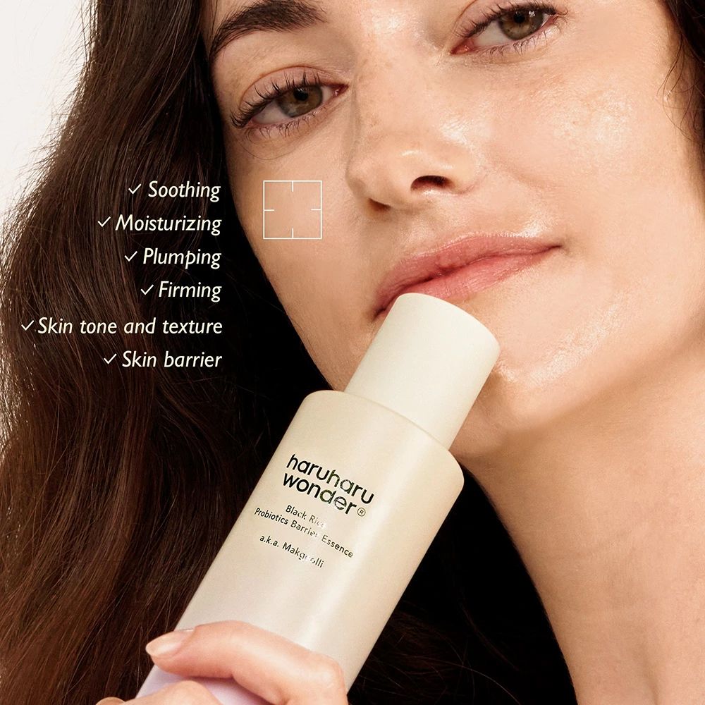 Vrouw houdt fles vast. Opschrift: haruharu wonder Black Rice Probiotics Barrier Essence. Tekst: Soothing, Moisturizing, Plumping, Firming.