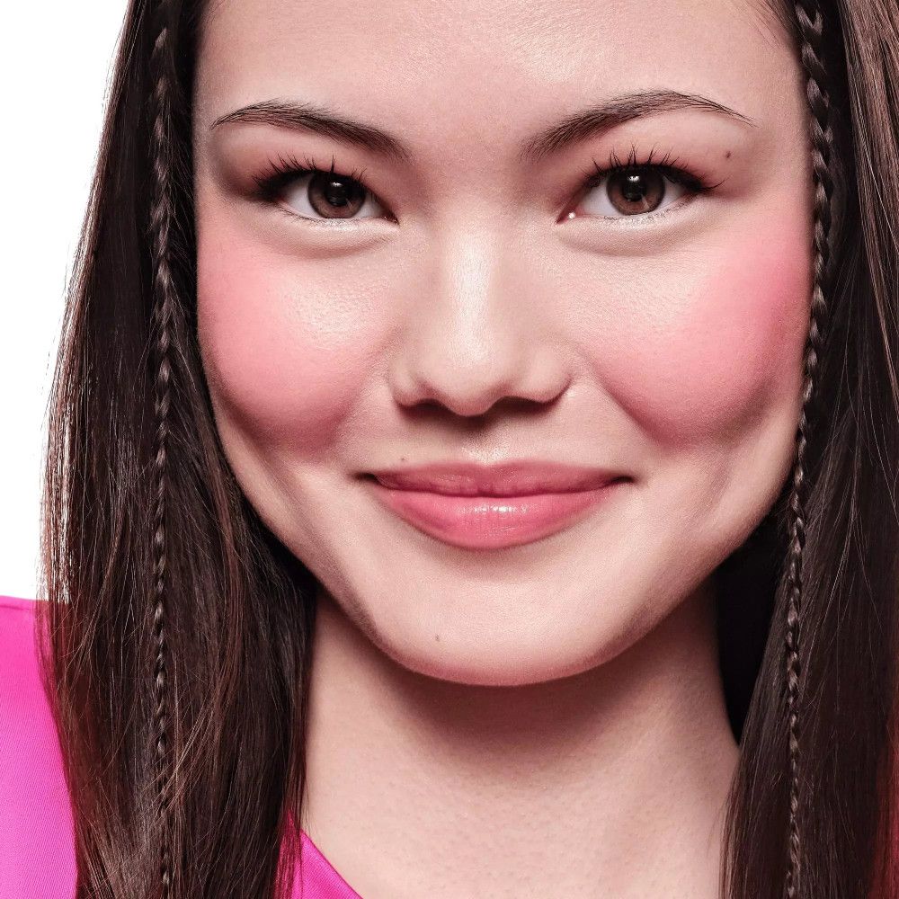 Portrait d'une femme avec du blush sur les joues. Elle a des tresses dans les cheveux.