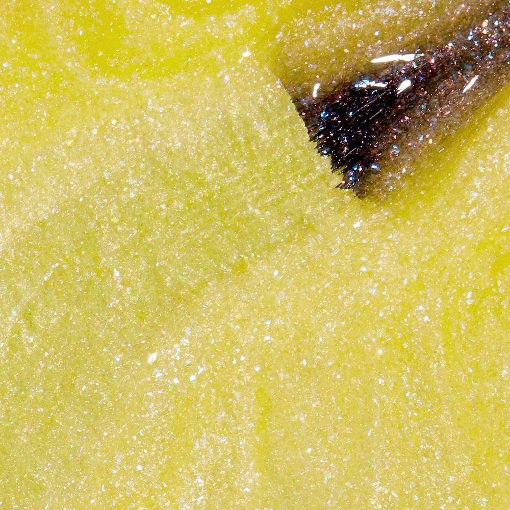 Nagellak applicator met gele lak op gele achtergrond. De borstel is bedekt met glitter.