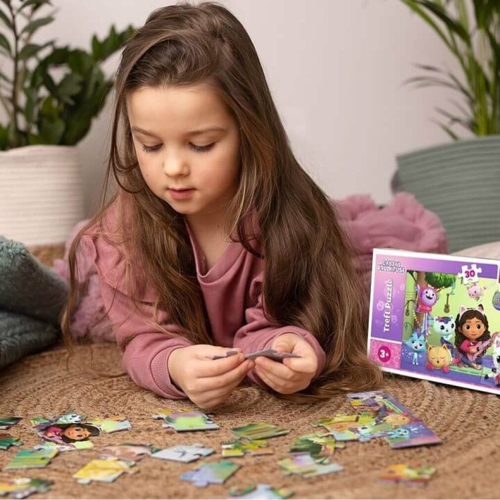 Enfant faisant un puzzle. Puzzle avec Gabby et des personnages de chats. Pièces de puzzle au sol. Emballage en arrière-plan.