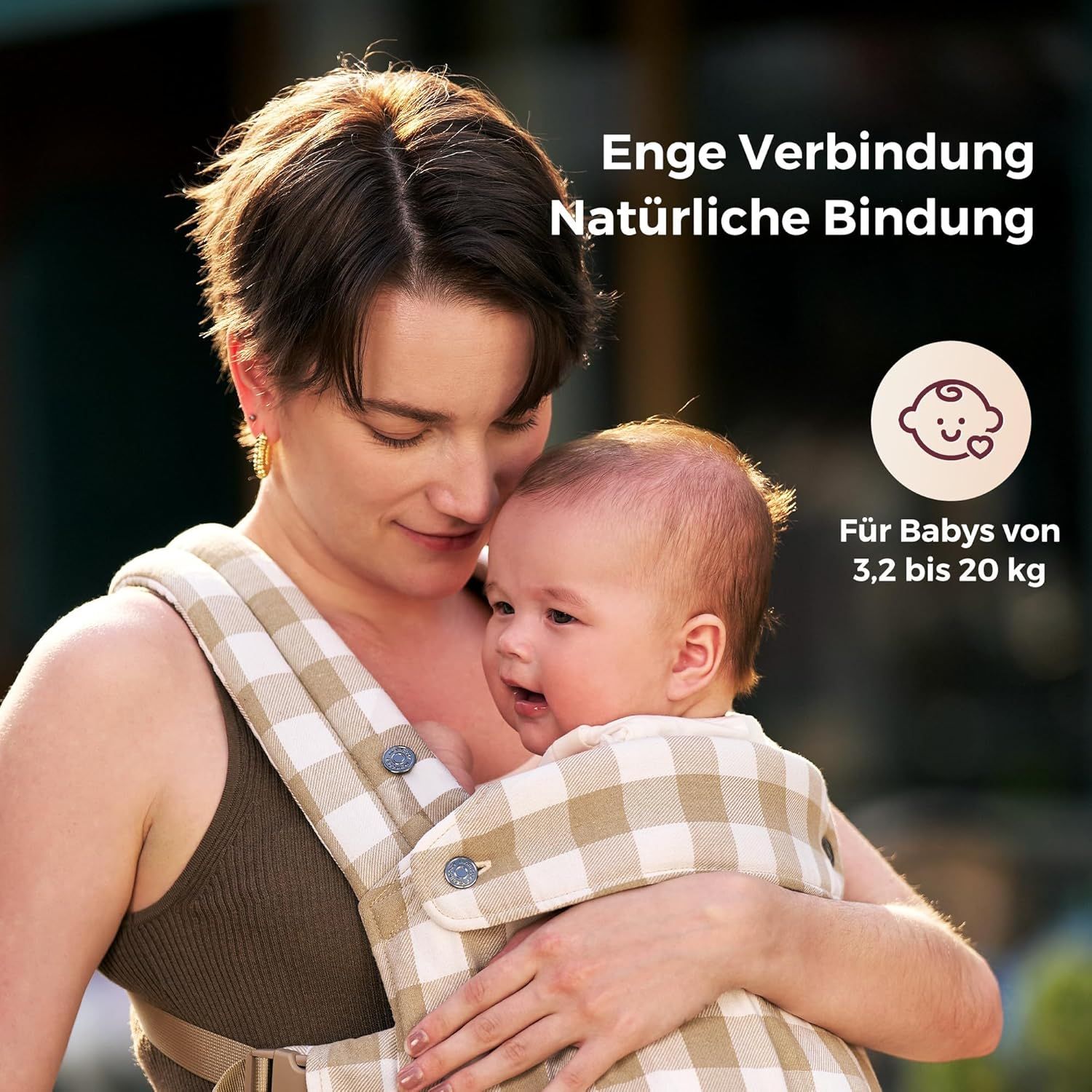 Vrouw met baby in babydrager met leisteen-ruitpatroon. Tekst: Nauwe band, Natuurlijke verbinding.