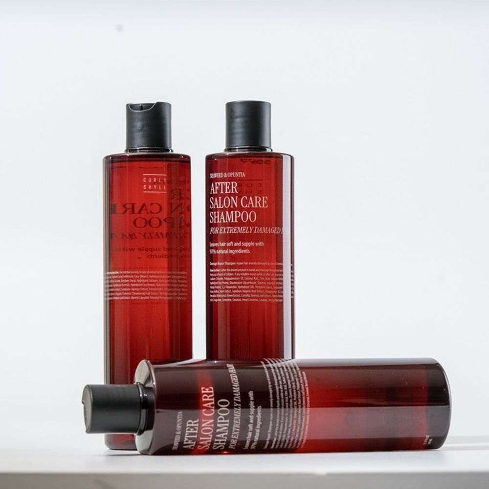 Drie bruine shampoo flessen met zwarte dop. Opschrift: After Salon Care Shampoo voor extreem beschadigd haar. Liggende fles.