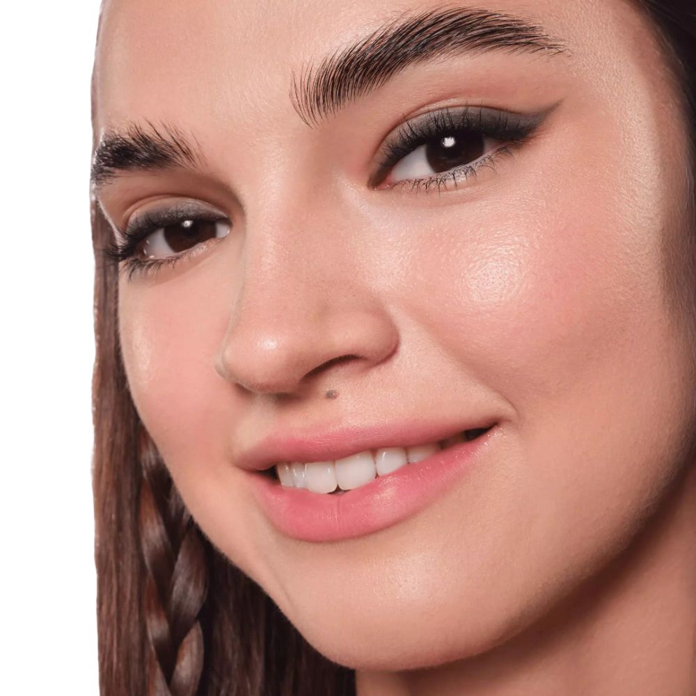 Gros plan d'un visage avec eyeliner. Yeux bruns, cils foncés, sourcils dessinés.