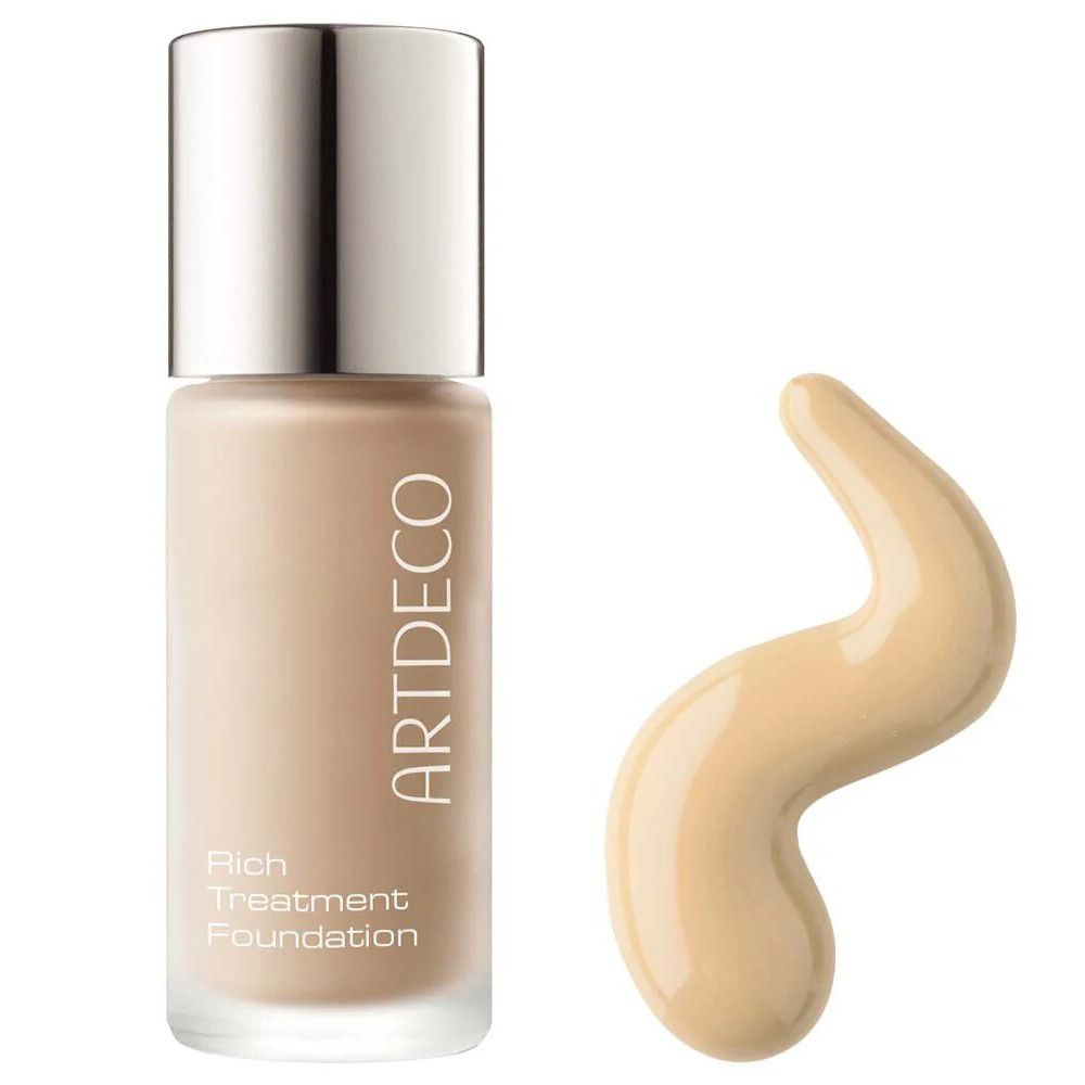 Artdeco Rich Treatment Foundation. Flacon avec bouchon argenté et produit à côté. Produit en forme de vague.