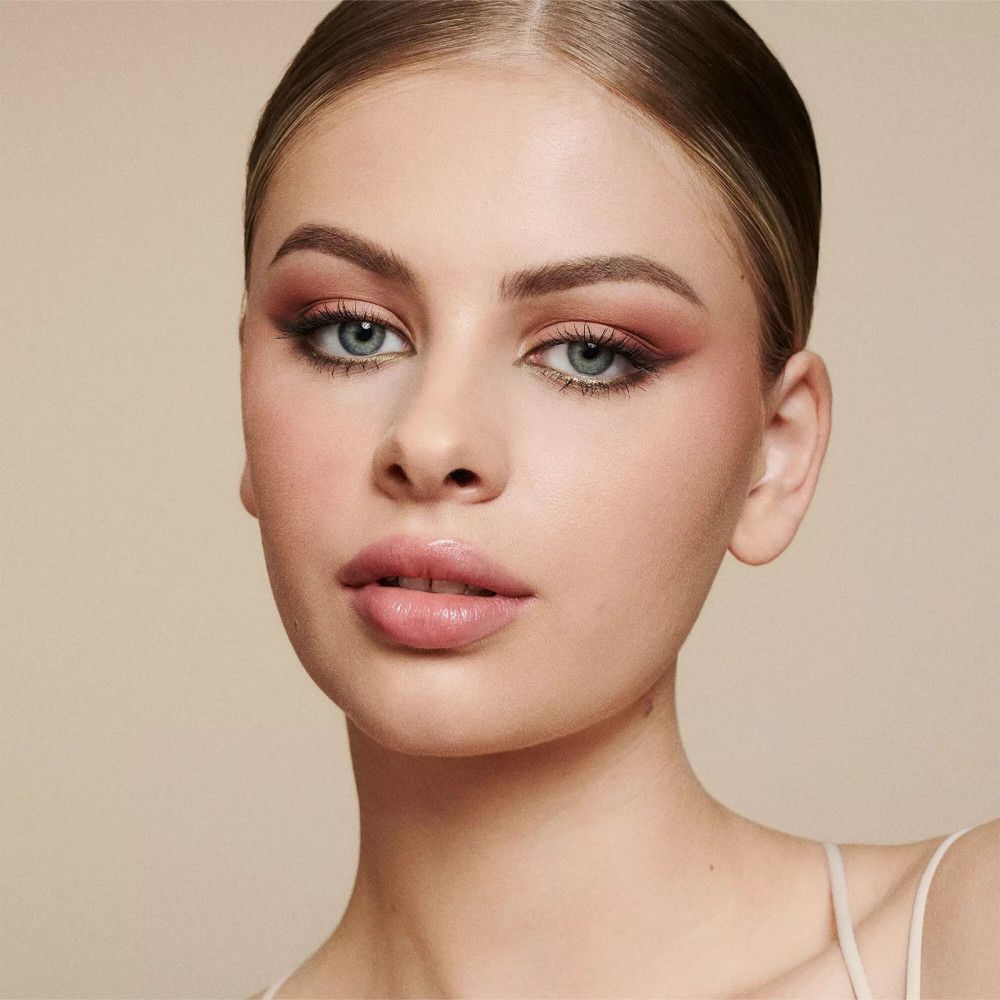 Portrait d'une femme maquillée. Yeux soulignés au crayon khôl. Rouge à lèvres. Fond clair.