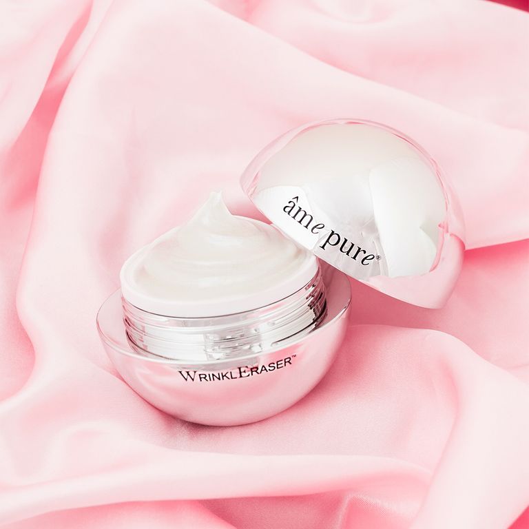 Un pot argenté ouvert avec crème blanche sur soie rose. Étiqueté "âme pure WrinklEraser".