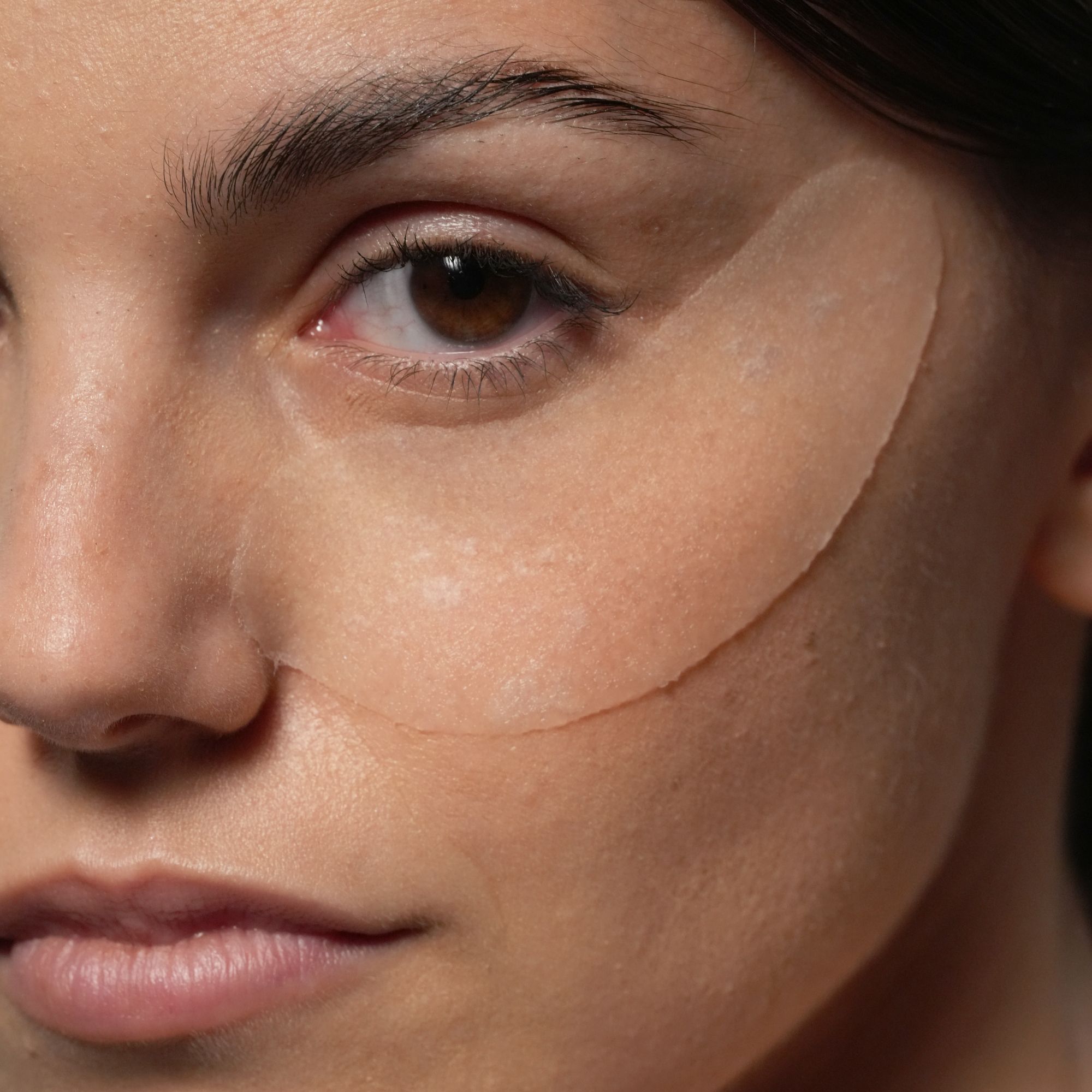 Gros plan d'une femme portant des patchs oculaires transparents sous les yeux.