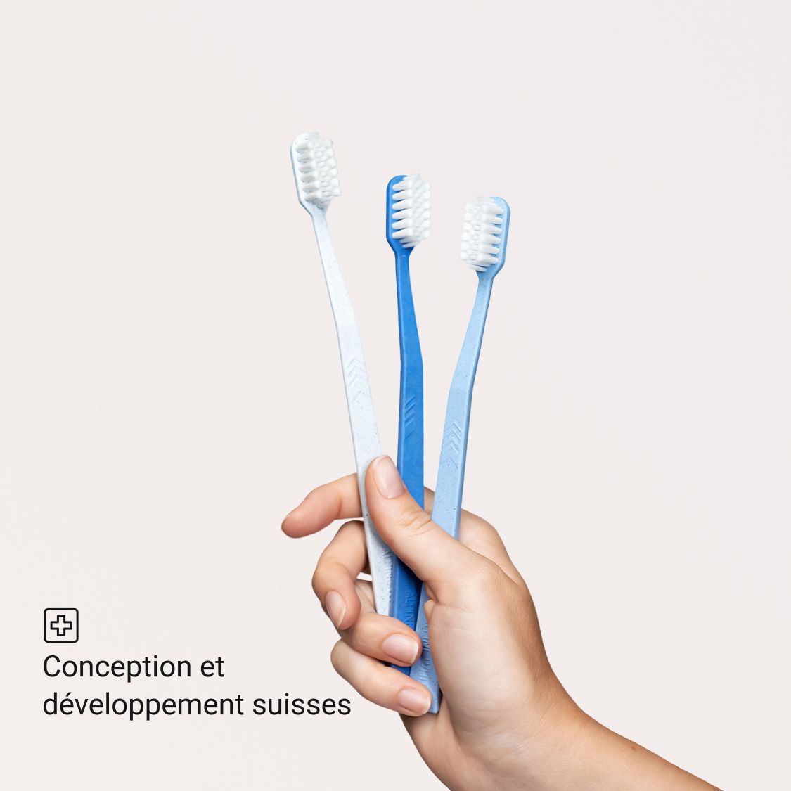 Trois brosses à dents bleues de différentes nuances. Tenues dans une main.