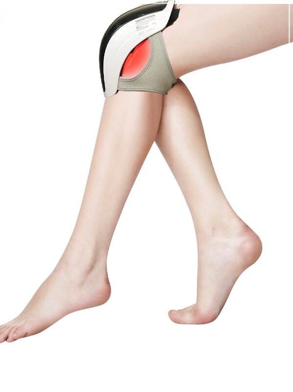 Knie-massageapparaat op been. Apparaat op knie, rood licht zichtbaar. Been in beeld.