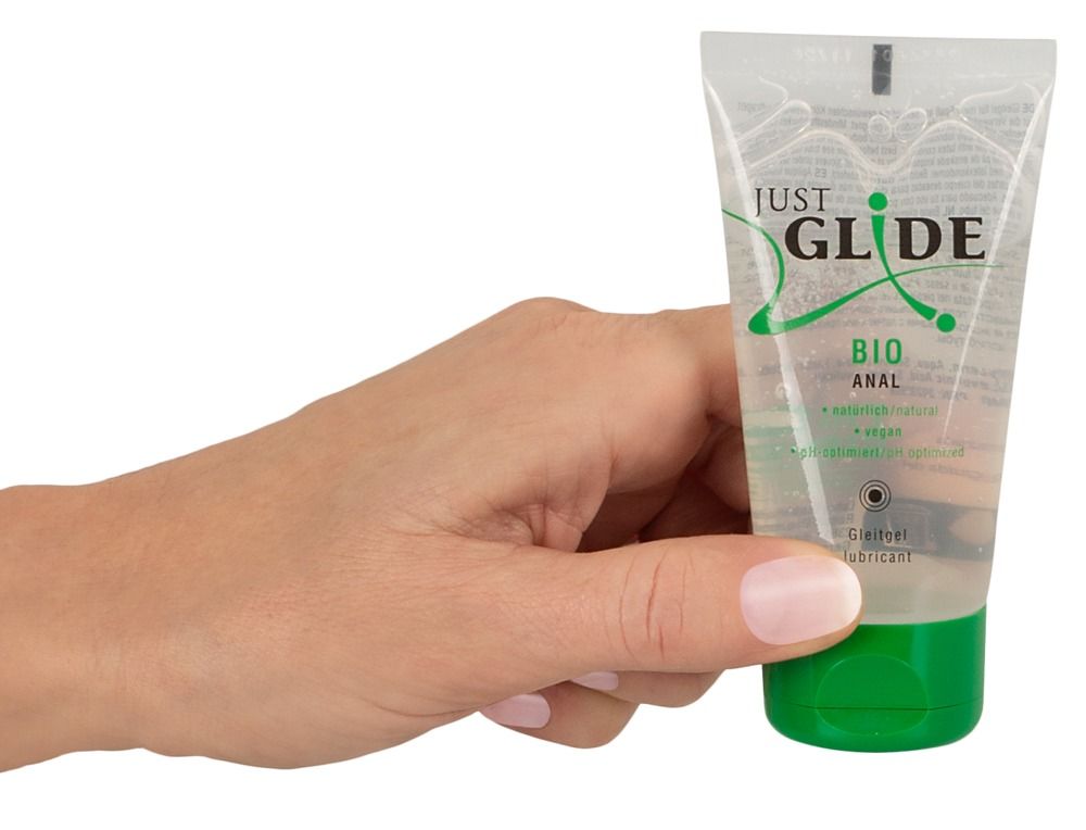Hand houdt een tube met groene dop vast. Opschrift: JUST GLIDE BIO ANAL. Product in transparante verpakking.