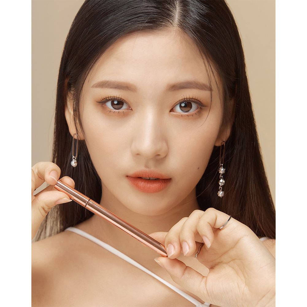 Femme tenant un stylo eyeliner. Couleur or rose. Inscription BLACK ROUGE.