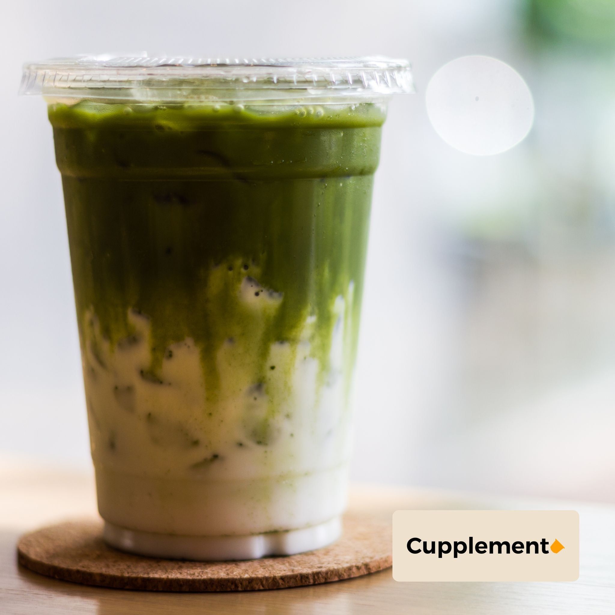 Glas met groene matcha drank. Cupplement logo rechtsonder.