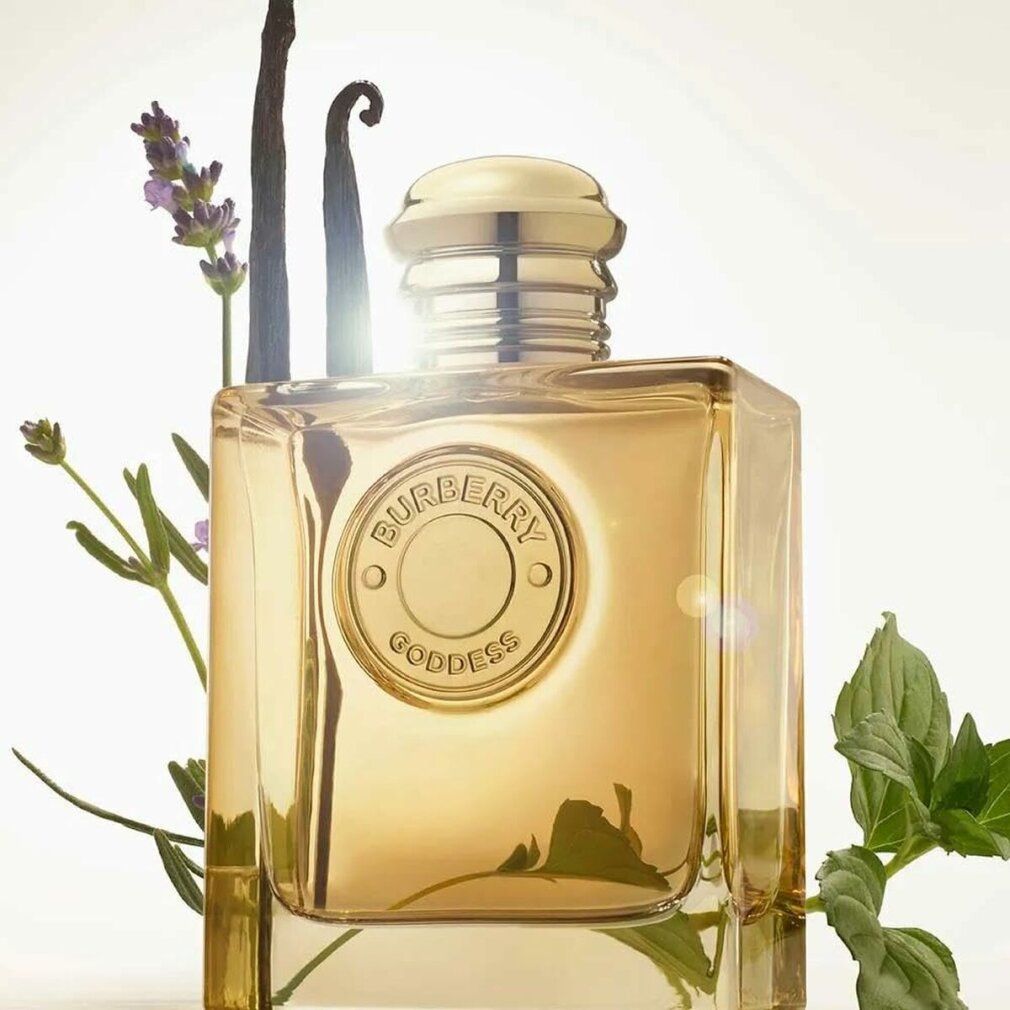 Burberry Goddess Intense Eau de Parfum. Flacon carré, bouchon doré. Emblème logo. Lavande, vanille et feuilles en arrière-plan.