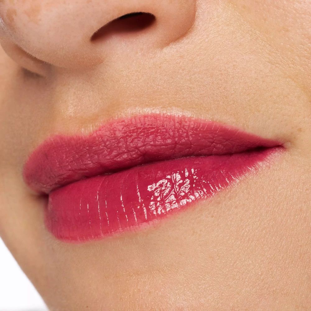 Gros plan sur des lèvres avec un Lip Tint rose brillant. Peau autour des lèvres visible.