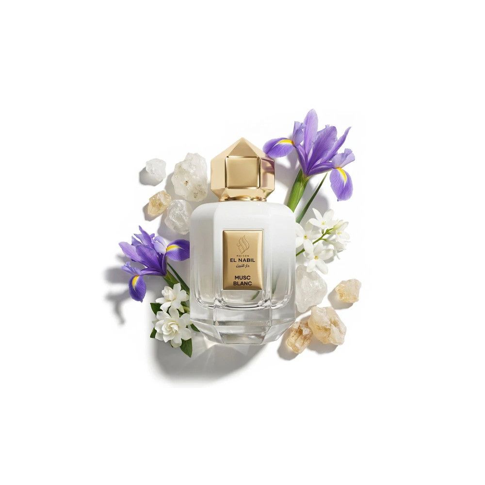 Flacon en verre blanc avec bouchon doré, entouré de fleurs blanches et violettes et de cristaux. Étiquette "EL NABIL MUSC BLANC".