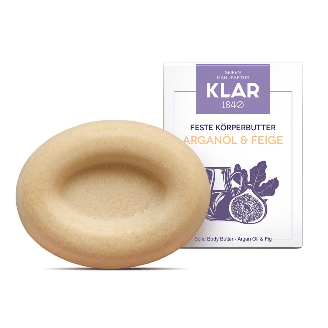 Ovale, vaste body butter. Lichtbeige kleur, met een concave verdieping. Naast de verpakking met productnaam: Arganolie & Vijg.