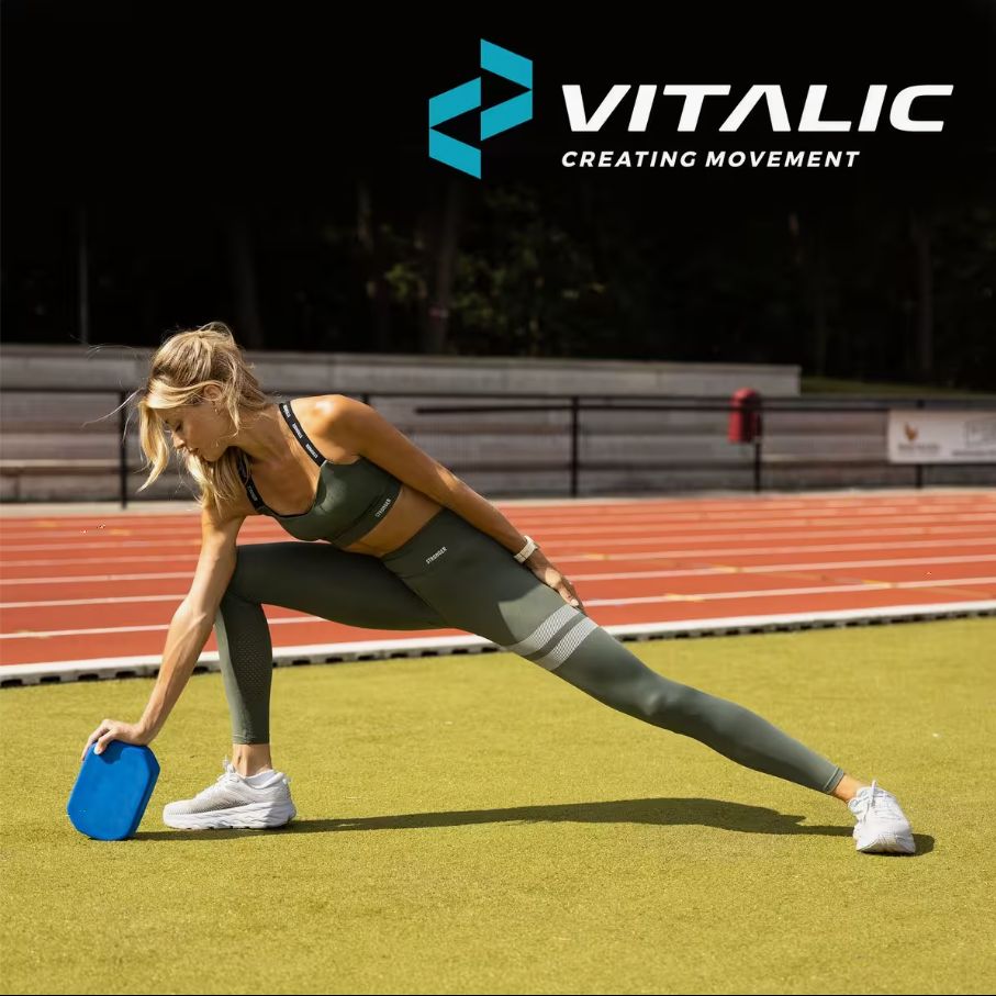 Bloc de yoga bleu en mousse. Femme en posture de yoga, bloc comme support. Logo VITALIC en arrière-plan.