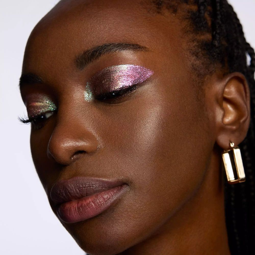 Gros plan d'une femme aux yeux fermés. De l'ombre à paupières chatoyante est appliquée sur les paupières.