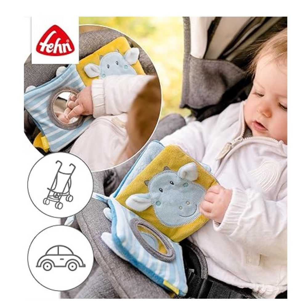 Baby zit in de kinderwagen en speelt met stoffen boeken. Merk: fehn. Met spiegels en diermotieven. Op de achtergrond: kinderwagen.