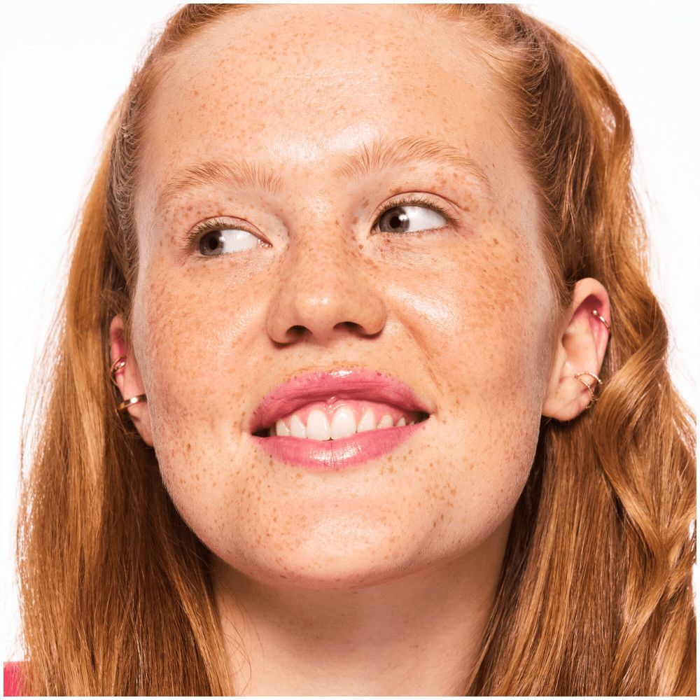 Portrait d'une femme rousse avec des taches de rousseur, regardant de côté. Rouge à lèvres rose.