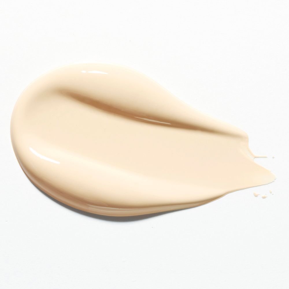 Vlek van lichtbeige foundation op witte achtergrond. De textuur is glad en glanzend.