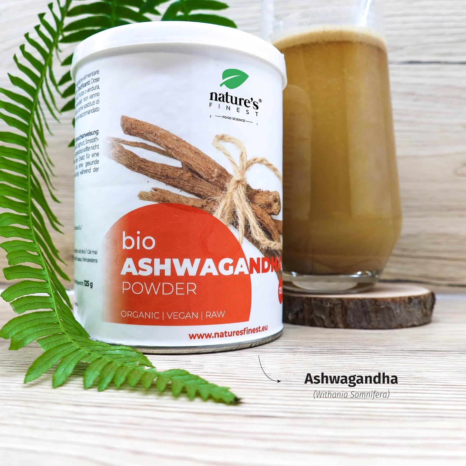 Potje bio Ashwagandha poeder, glas water, lepel met poeder. Opschrift Nature's Finest. Instructies.