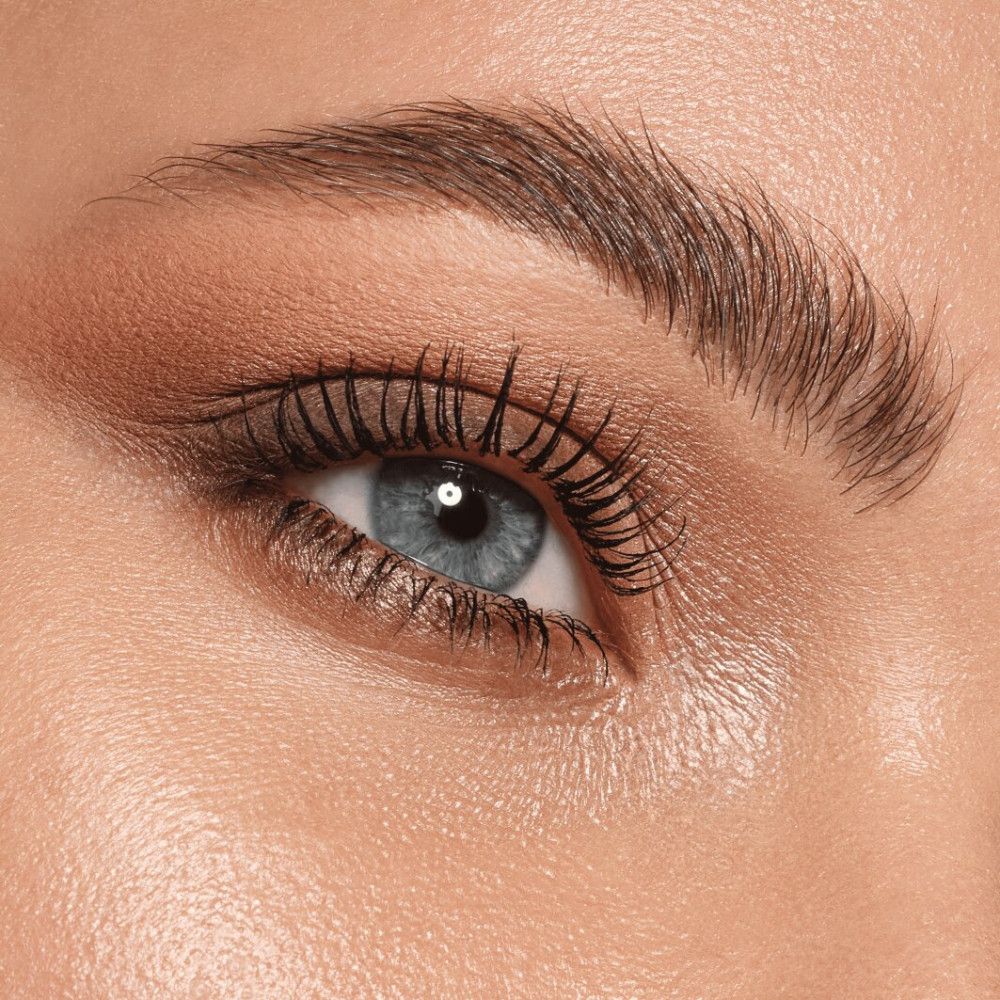 Close-up van een oog met oogschaduw. Blauwe oogkleur, bruine wenkbrauwen. Gemaakte wimpers.