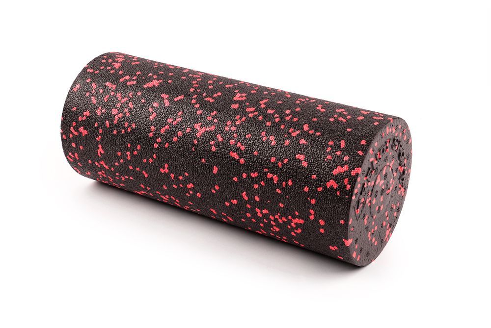 Rouleau de fascia, cylindrique, noir avec des points rouges. En mousse. Repose sur fond blanc.