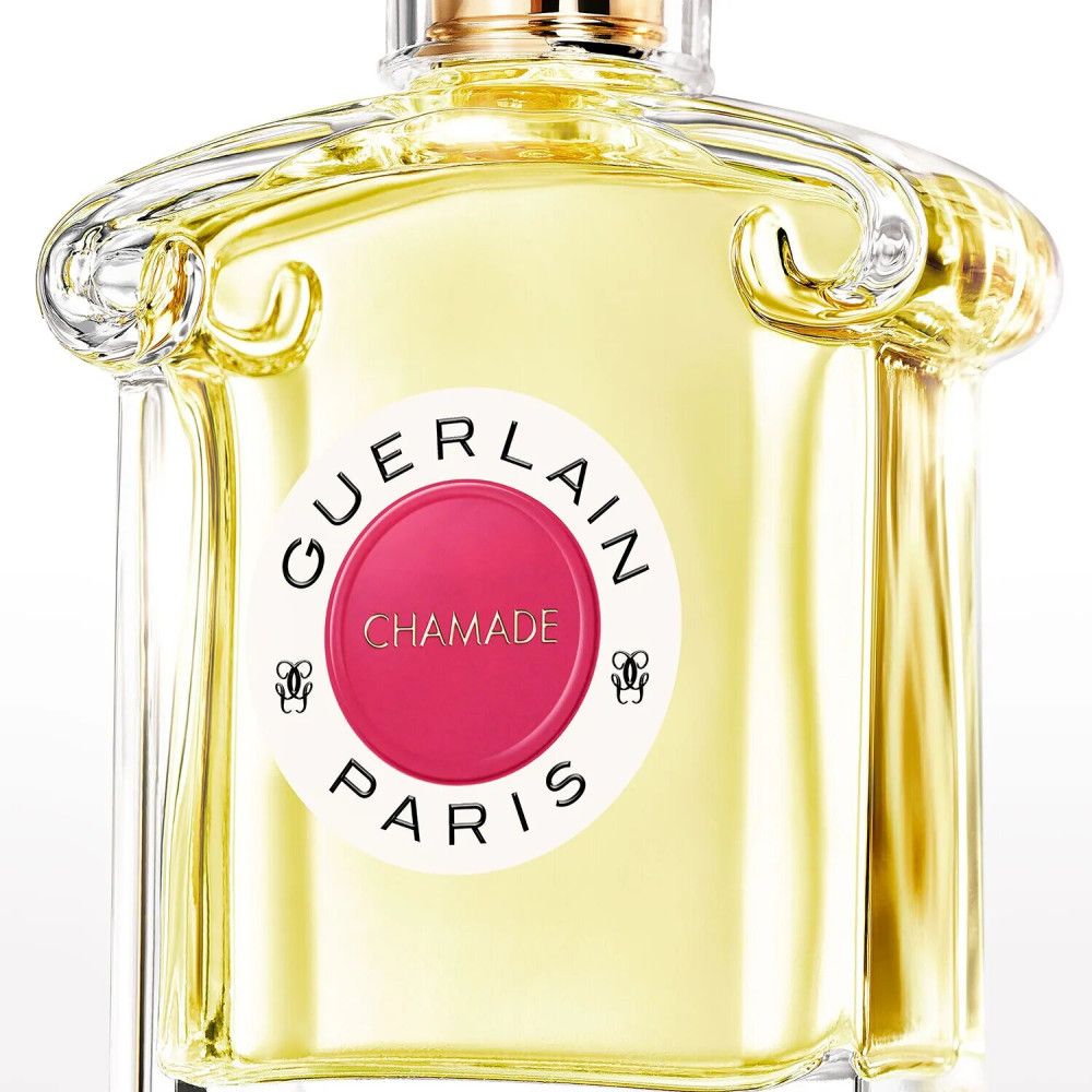 Gros plan sur le flacon de parfum. Étiquette rouge avec inscription : Guerlain Chamade Paris. Liquide jaune.