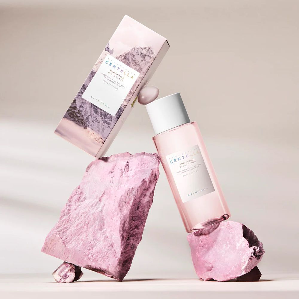 Fles en verpakking op roze stenen. Verpakking met bergmotief. Fles met tekst: CENTELLA, SKIN1004.