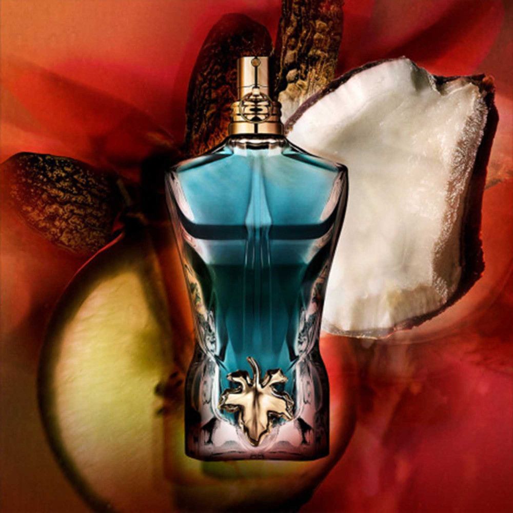 Flacon Jean Paul Gaultier "Le Beau" en forme de torse masculin. Détails dorés. Sur fond rouge.