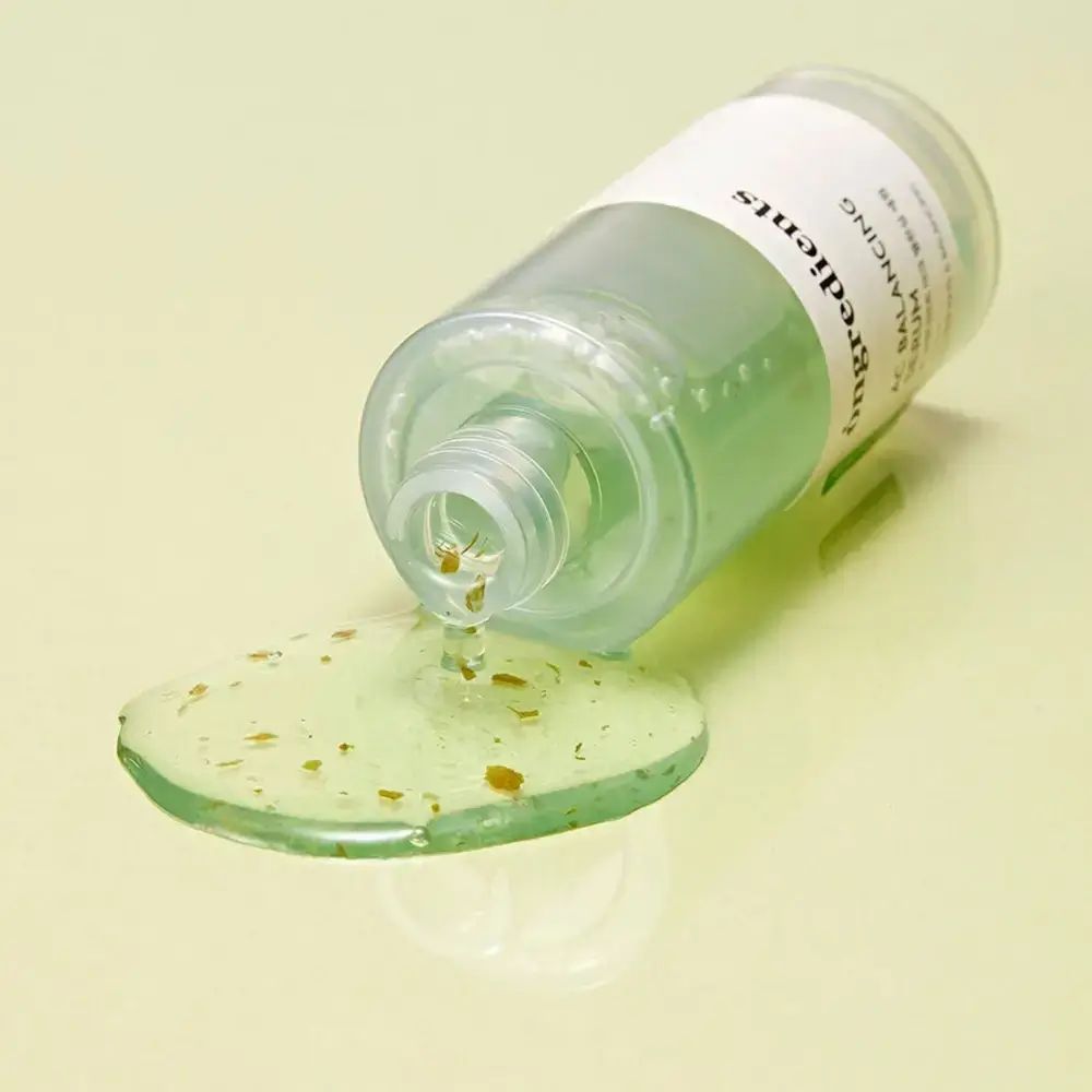 Serumfles ligt. Groen serum met deeltjes vloeit eruit. Opschrift: Ongredients AC Balancing Serum.