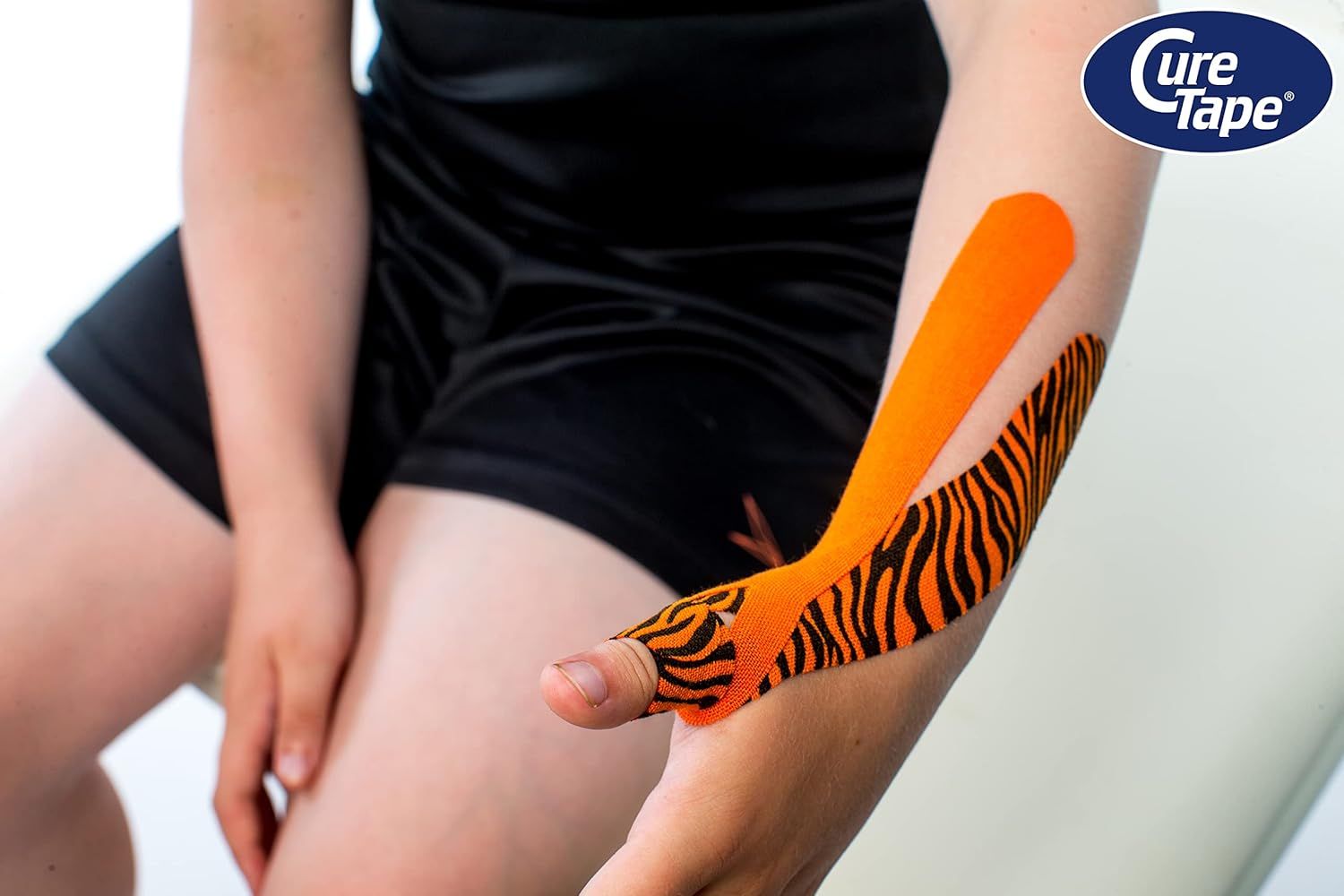 CureTape kinesiologie tape met tijgerprint, aangebracht op de onderarm. Toont de flexibele tape-applicatie.