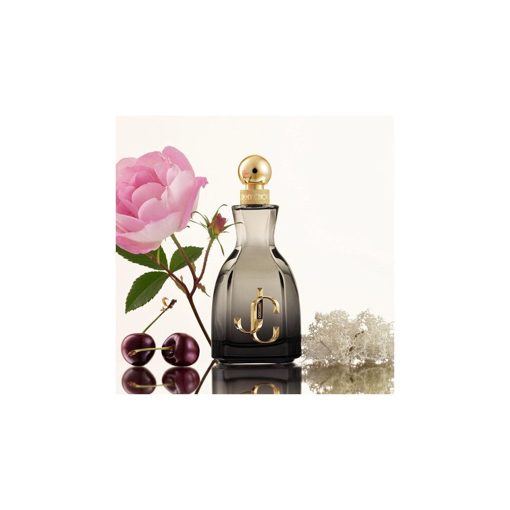 Flacon de parfum avec bouchon doré et logo. À côté, une rose, des cerises et des fleurs.